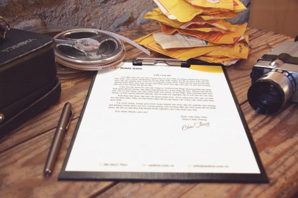 Una lettera firmata su una cartellina, accanto a una penna stilografica su una scrivania di legno