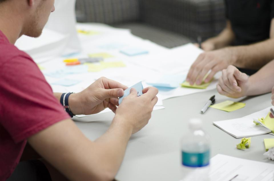 Colleagues around a table with sticky notes and papers during a meeting