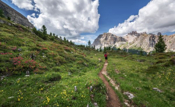 Uma pessoa numa trilha de montanha rumo aos picos das Dolomitas