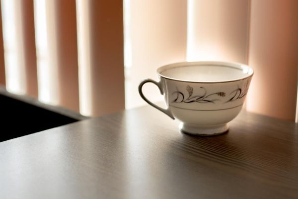 Uma xícara de chá de porcelana branca sobre uma mesa perto da janela