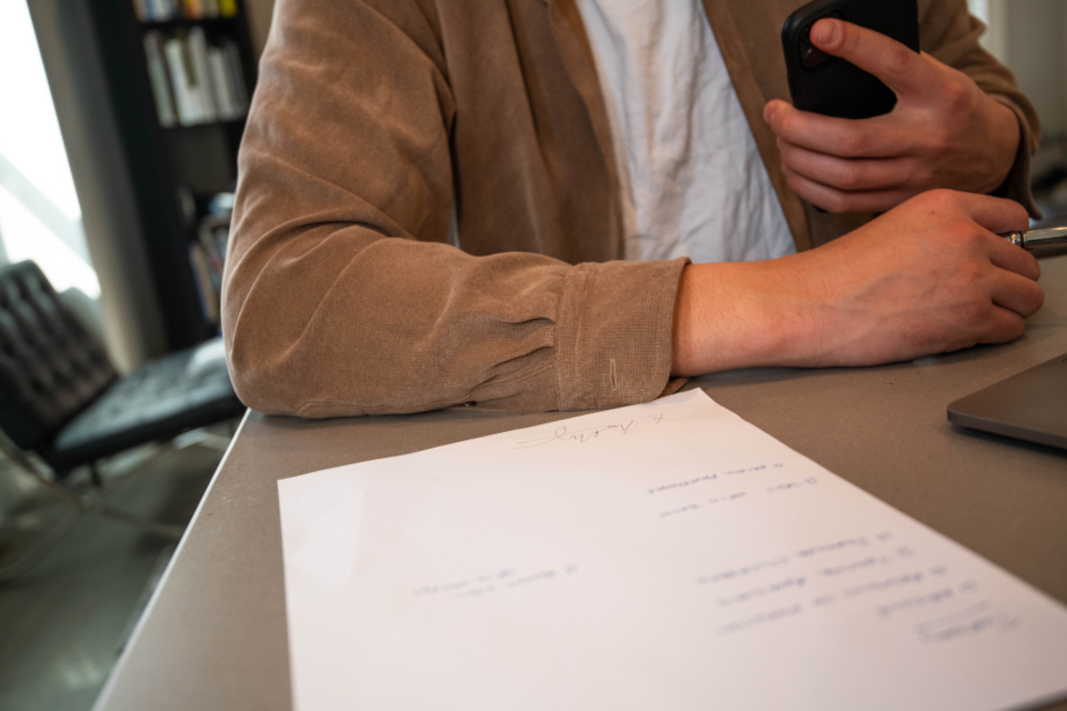 A man at a desk with a handwritten sheet of paper in front of him