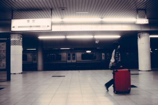 Una persona que arrastra una maleta roja por un andén en Tokio