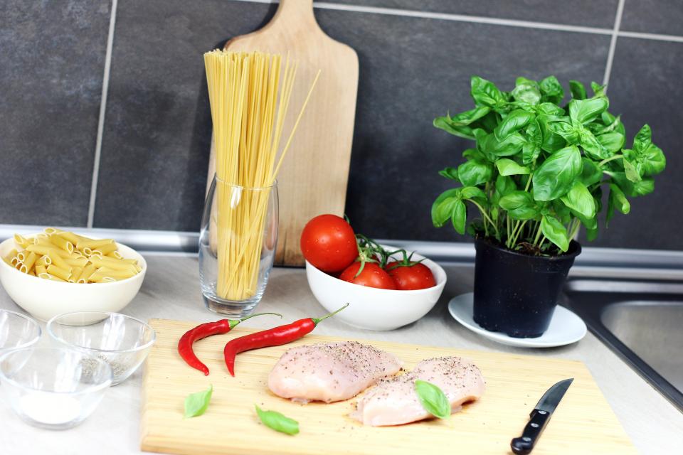 Pasta, tomatoes, basil and chicken laid out on a kitchen counter