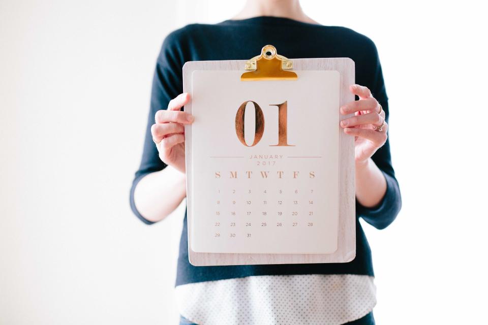 Una donna che tiene un calendario su una cartellina aperto al primo gennaio